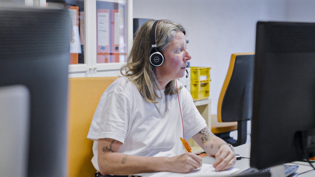 Eine Frau mit Kopfhörern im Büro.